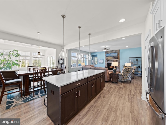 kitchen with light wood-style flooring, a fireplace, light countertops, and freestanding refrigerator