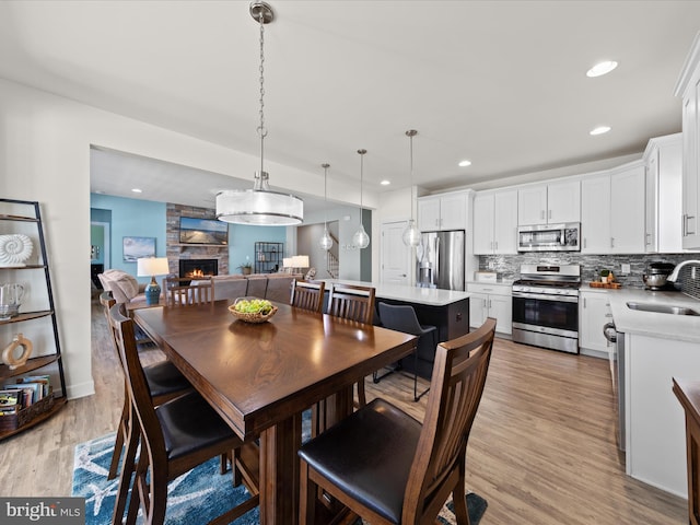 dining space featuring recessed lighting, a fireplace, and light wood-type flooring