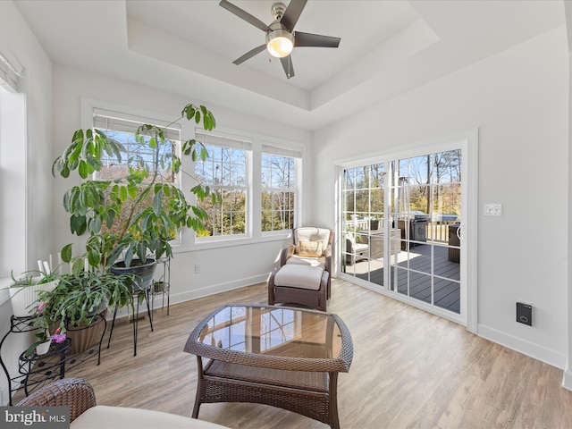 sitting room with plenty of natural light, light wood-type flooring, and a raised ceiling