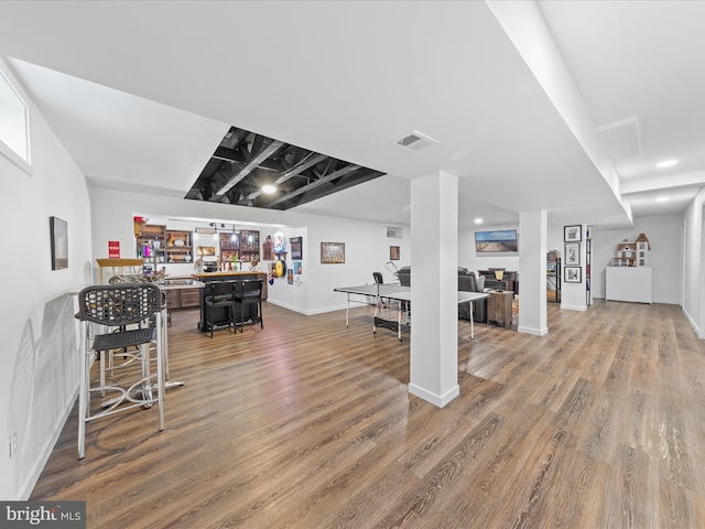 rec room with visible vents, a bar, baseboards, and wood finished floors