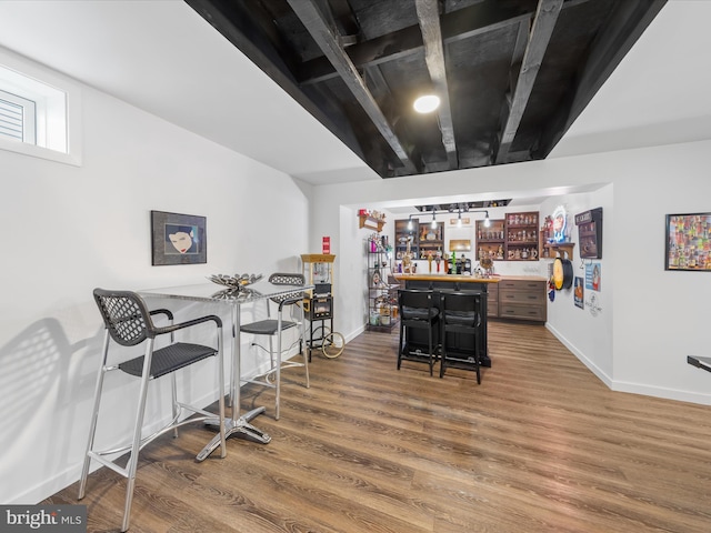 bar featuring baseboards, wood finished floors, and a dry bar