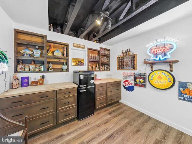 bar with baseboards, light wood-style floors, and freestanding refrigerator