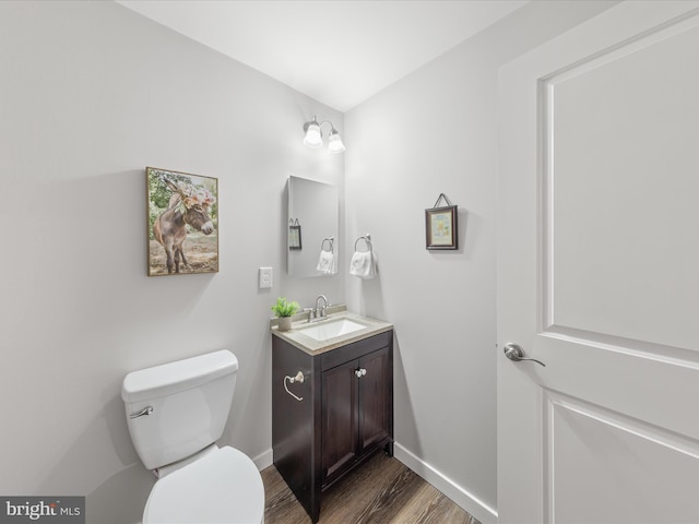 bathroom with vanity, toilet, wood finished floors, and baseboards