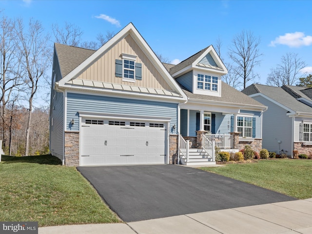 craftsman-style home with board and batten siding, aphalt driveway, a porch, a front yard, and stone siding