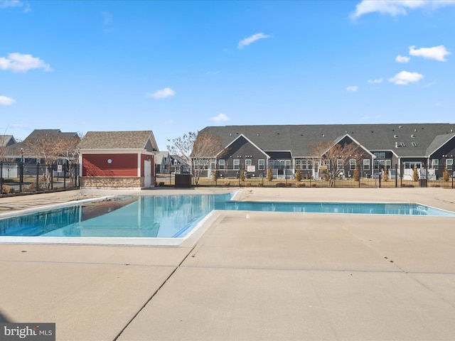 community pool featuring a patio, fence, and a residential view