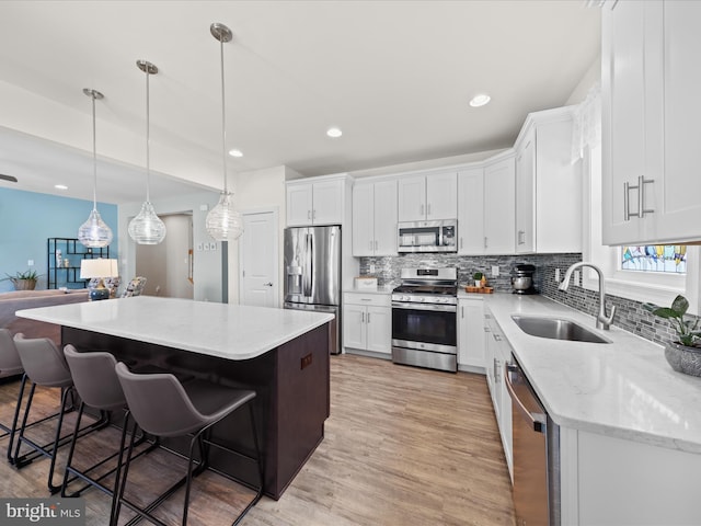 kitchen with white cabinets, stainless steel appliances, light wood-style floors, and a sink