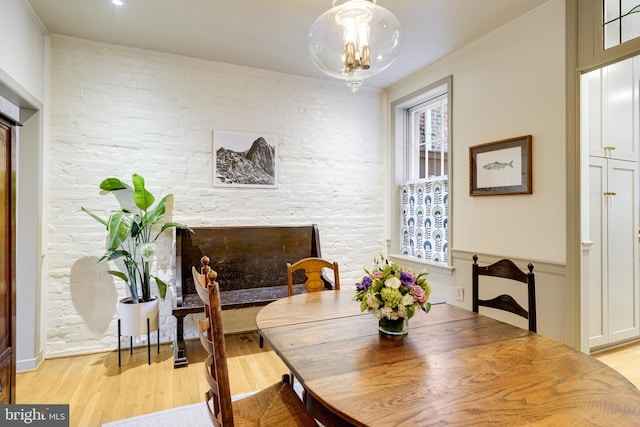 dining area with light wood-style flooring, a healthy amount of sunlight, ornamental molding, and a chandelier