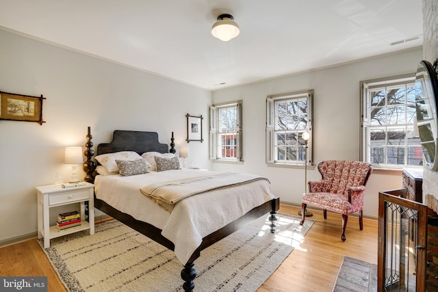 bedroom with visible vents, multiple windows, baseboards, and light wood-style floors