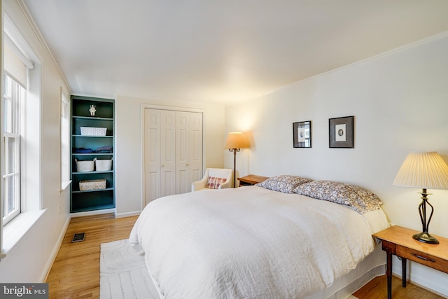 bedroom with visible vents, a closet, light wood finished floors, and baseboards