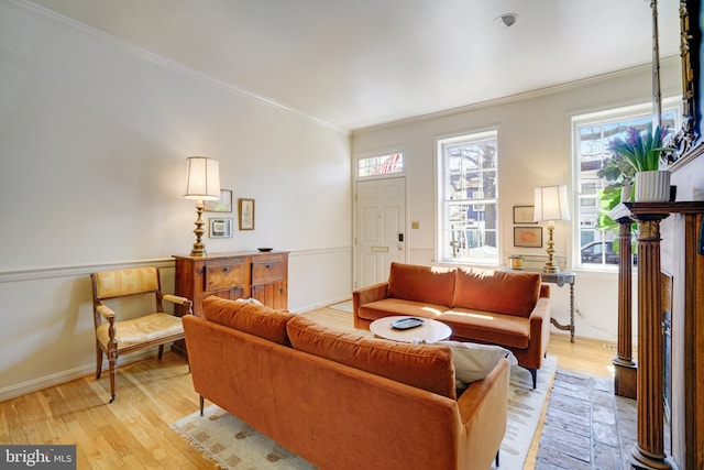 living area featuring light wood-style flooring, baseboards, and ornamental molding