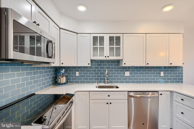 kitchen featuring a sink, stainless steel appliances, tasteful backsplash, and light countertops