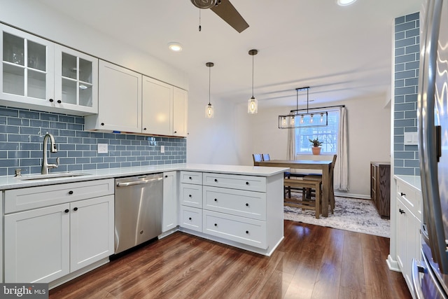 kitchen featuring a sink, backsplash, light countertops, appliances with stainless steel finishes, and dark wood-style flooring