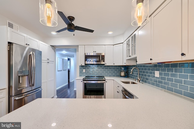 kitchen featuring light stone counters, visible vents, a sink, stainless steel appliances, and backsplash