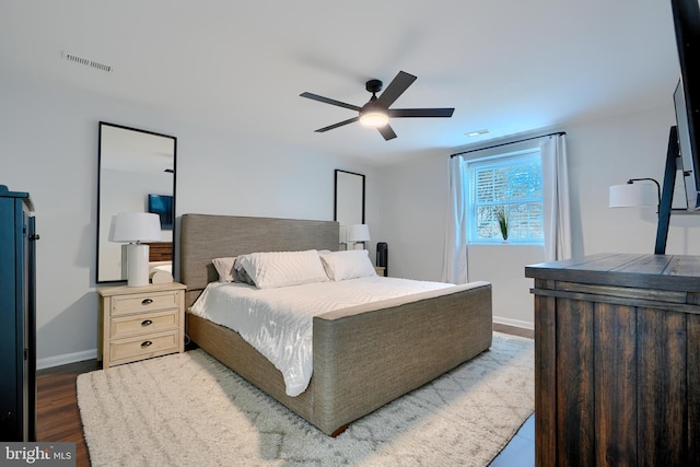 bedroom with visible vents, baseboards, wood finished floors, and a ceiling fan