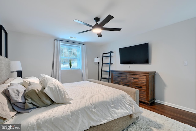 bedroom featuring a ceiling fan, visible vents, wood finished floors, and baseboards