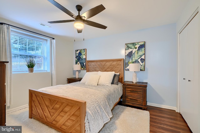 bedroom with wood finished floors, visible vents, baseboards, ceiling fan, and a closet