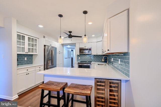 kitchen featuring glass insert cabinets, beverage cooler, light countertops, appliances with stainless steel finishes, and a sink