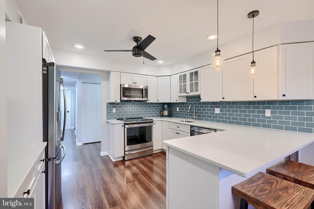 kitchen featuring a peninsula, dark wood-style flooring, a sink, stainless steel appliances, and white cabinets