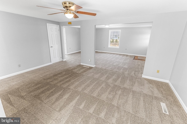 carpeted spare room with visible vents, baseboards, and ceiling fan