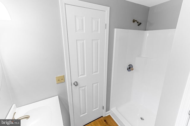 bathroom featuring wood finished floors, a shower, and a sink