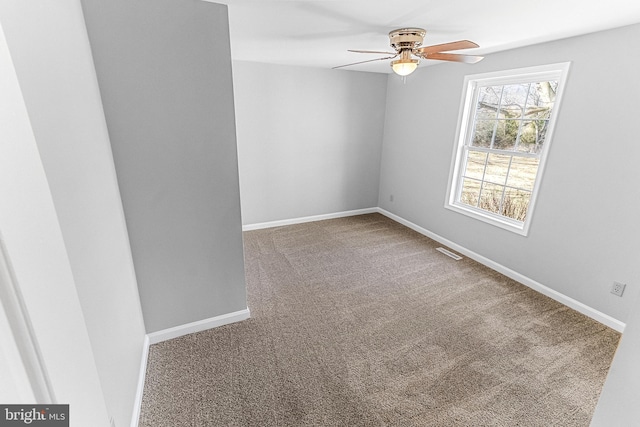 carpeted spare room with baseboards, visible vents, and ceiling fan