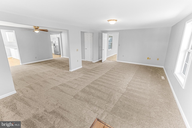 empty room with baseboards, a ceiling fan, a healthy amount of sunlight, and carpet flooring