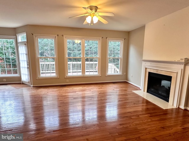 unfurnished living room featuring baseboards, wood-type flooring, a ceiling fan, and a fireplace