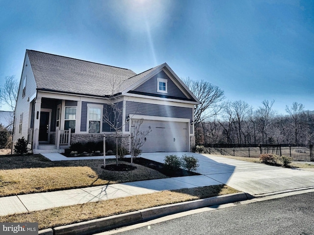 view of front facade with a shingled roof, concrete driveway, a garage, and fence