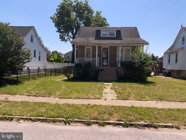 bungalow-style home featuring a porch, fence, and a front lawn