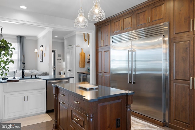 kitchen with visible vents, a sink, stainless steel appliances, dark countertops, and a center island