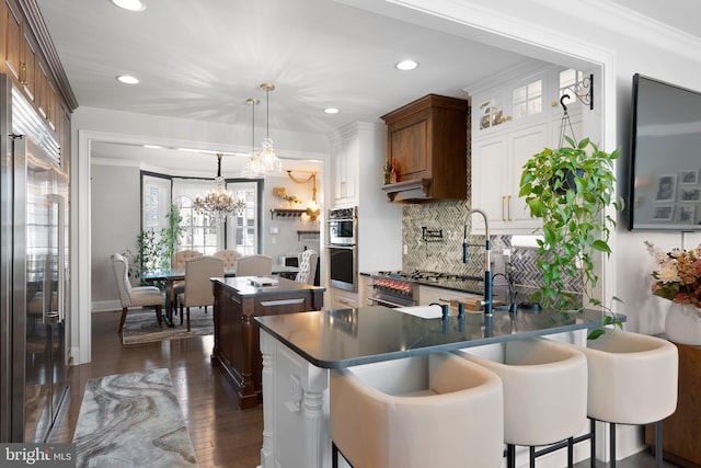 kitchen with dark wood finished floors, a breakfast bar, ornamental molding, appliances with stainless steel finishes, and dark countertops