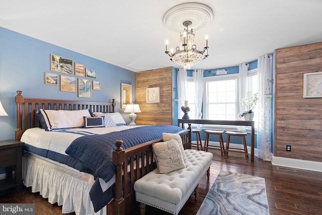 bedroom featuring baseboards, wood-type flooring, an inviting chandelier, and visible vents