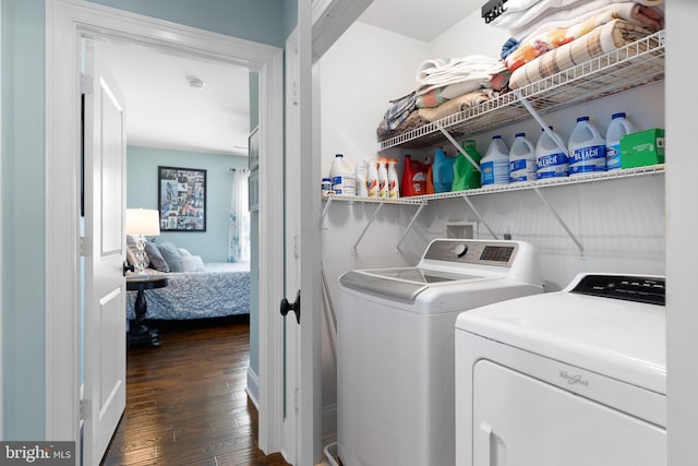 clothes washing area with dark wood-style floors, laundry area, and washer and clothes dryer