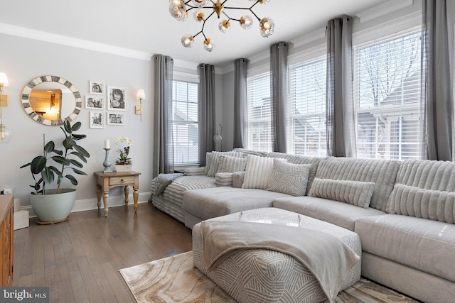 living room with hardwood / wood-style floors, an inviting chandelier, baseboards, and ornamental molding