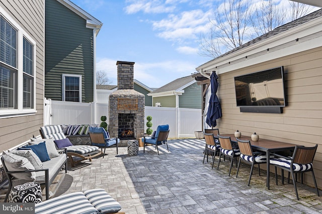 view of patio with a fenced backyard, outdoor dining space, and an outdoor living space with a fireplace