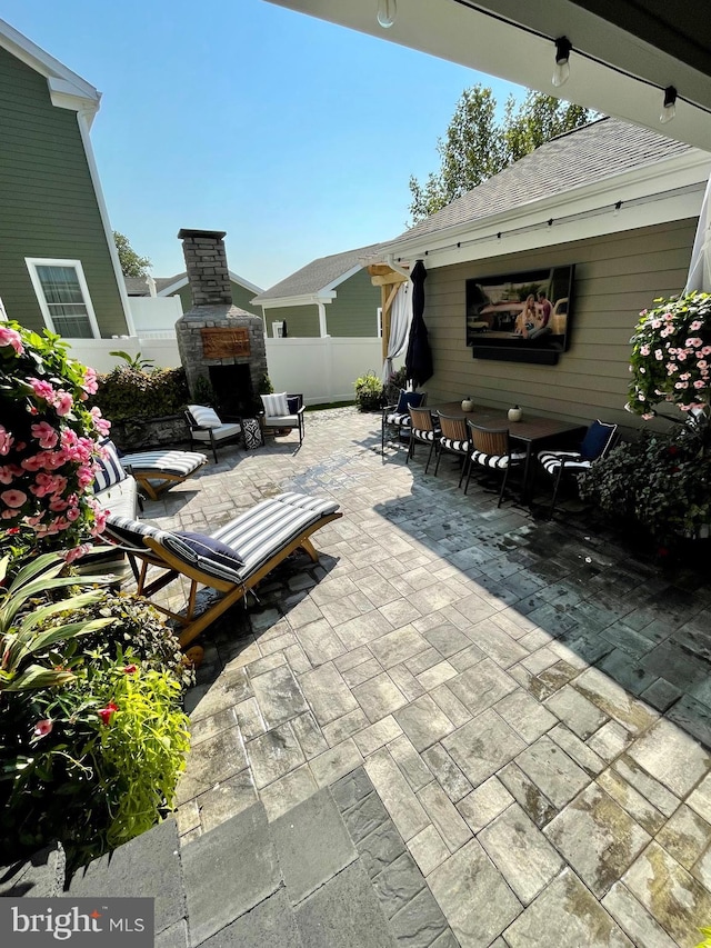 view of patio / terrace with fence and an outdoor stone fireplace