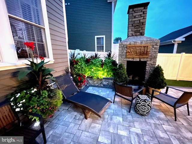 view of patio / terrace featuring an outdoor stone fireplace and fence