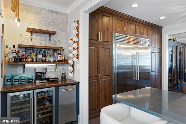 interior space featuring built in refrigerator, ornamental molding, tasteful backsplash, recessed lighting, and a bar