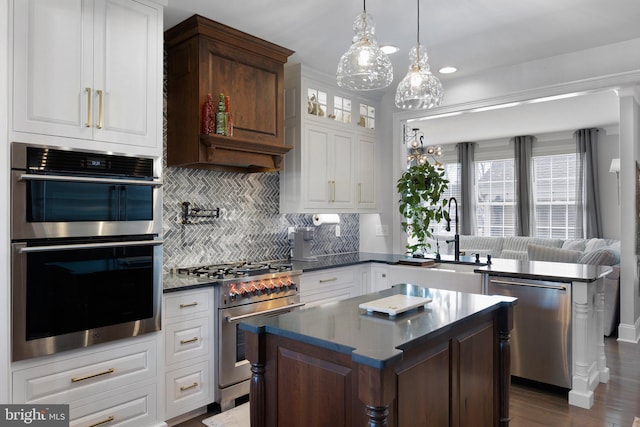 kitchen with a sink, a center island, white cabinetry, appliances with stainless steel finishes, and glass insert cabinets