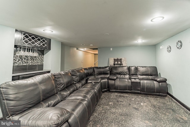 cinema room featuring a bar, speckled floor, and baseboards