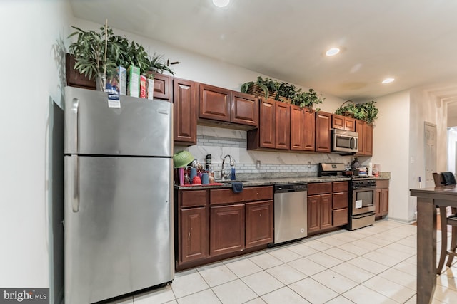 kitchen with a sink, light tile patterned floors, backsplash, and stainless steel appliances