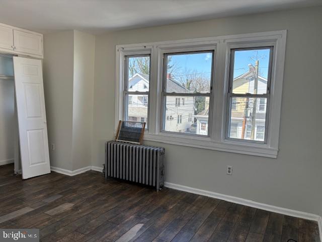 interior space with dark wood finished floors, radiator, and baseboards