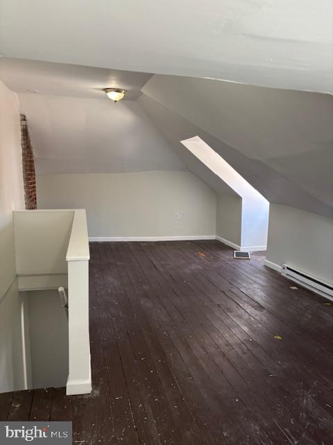 bonus room featuring a baseboard heating unit, wood-type flooring, baseboards, and vaulted ceiling