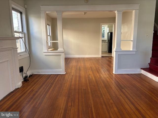 interior space featuring decorative columns, baseboards, hardwood / wood-style floors, and stairway