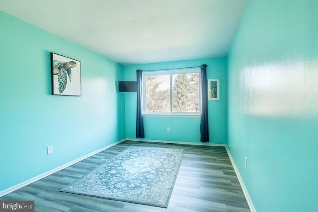 spare room featuring baseboards and wood finished floors