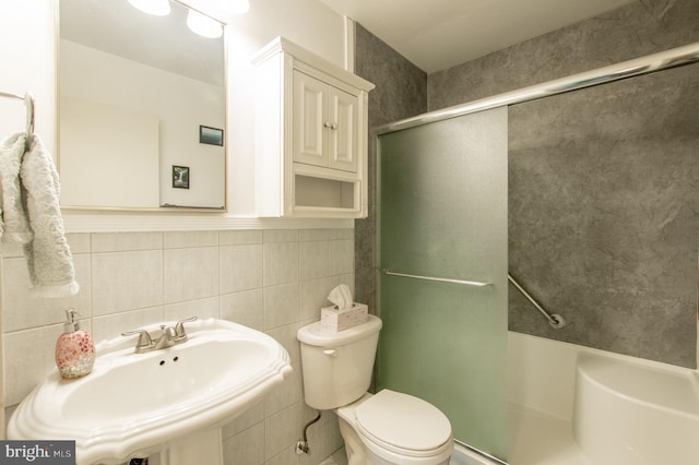 full bath with toilet, tile walls, an enclosed shower, and a sink