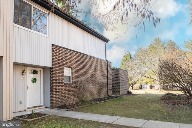 exterior space with brick siding and a lawn