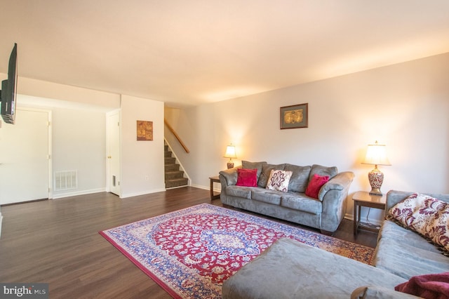 living room with stairway, wood finished floors, visible vents, and baseboards