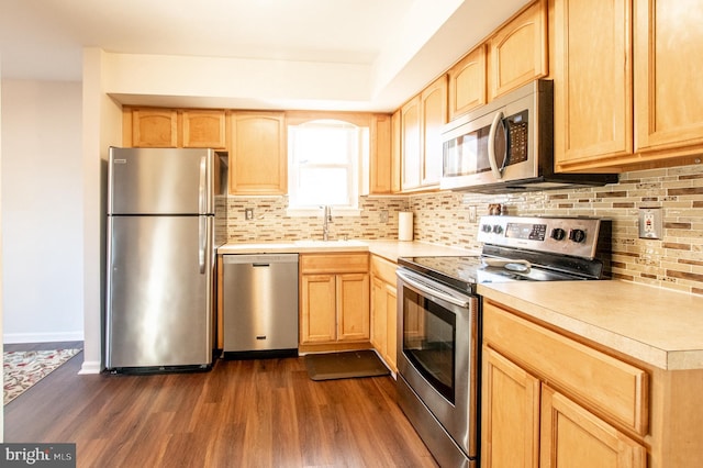 kitchen featuring stainless steel appliances, tasteful backsplash, dark wood-style floors, and light brown cabinetry