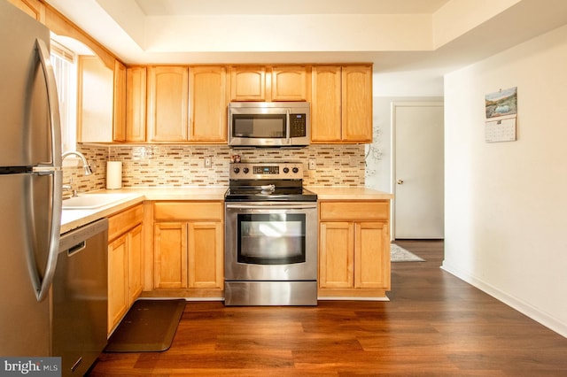 kitchen featuring backsplash, light brown cabinets, light countertops, appliances with stainless steel finishes, and a sink